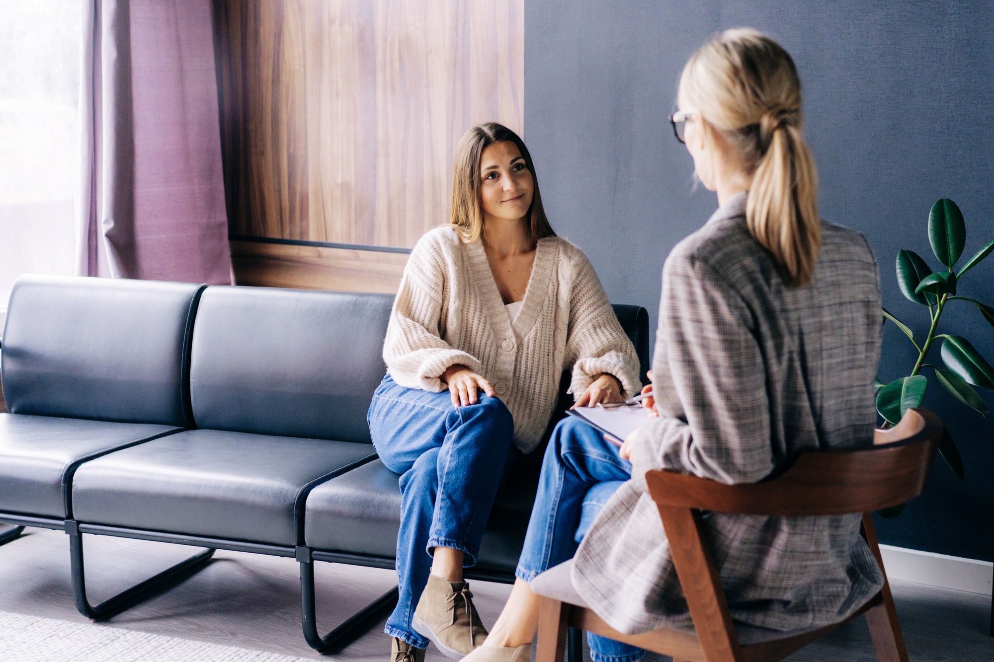 A smiling client is having a confidential conversation with a consultant psychologist.