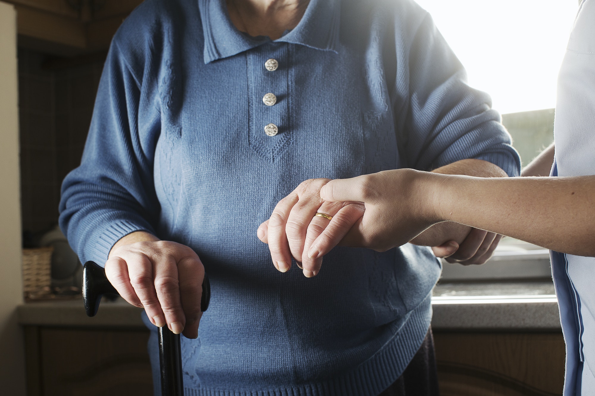 Personal care assistant supporting senior woman to walk